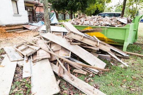 Workers clearing overgrown garden in Wallington with tools and waste bags